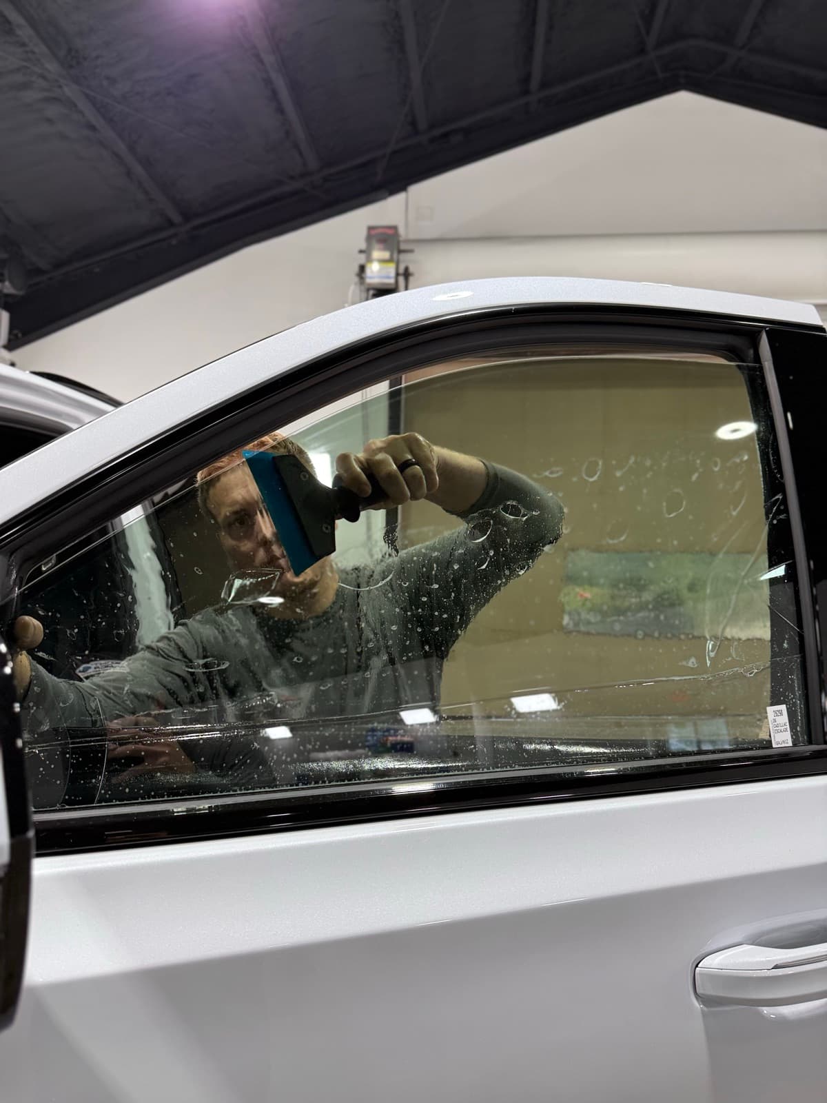 ATD Suncoast technician applying tint film to white car window